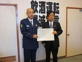 警官と田代町長が一緒に紙を持っている写真