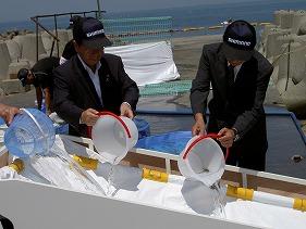 稚魚放流する田代町長(左)と安東販売促進部次長