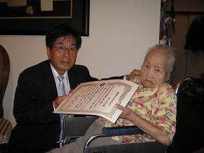 岬町の最高齢者辻キヨヱさんに表彰状を手渡す田代町長（左）