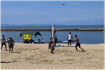 砂浜で男の人がボールを追いかけている写真