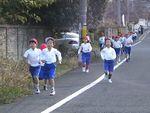 避難訓練で道路の脇を走っている子供たちの写真