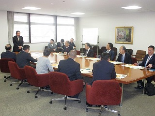 机を囲んで会議をしている男性の写真