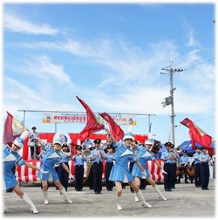 演奏者の前で踊る旗を持ったカラーガードの女性の写真